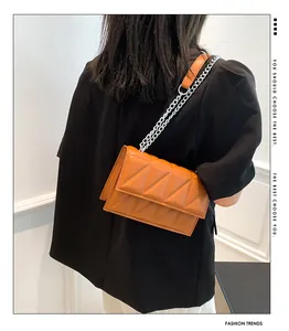 Detail van oranjebruine gewatteerde kunstlederen tas met geometrische stiksels en ketting