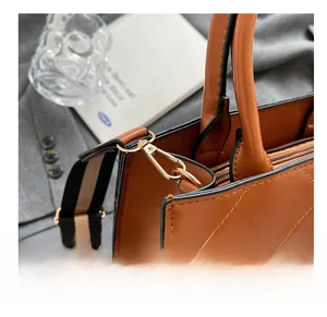 Close-up of golden hardware hooks and quilted brown leather texture with striped strap