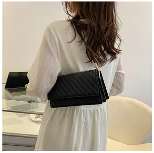 Detailed back view of a black quilted shoulder bag worn by a model in a modern office set