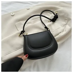 Dettaglio borsa in pelle nera con design imbottito scultoreo e hardware dorato