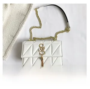 Detail view of white quilted faux leather bag with gold SS logo and metallic tassel