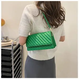 Detail of vibrant green quilted crossbody bag with gold hardware and slim strap