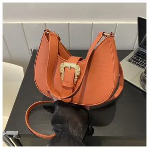 Close-up of burnt orange hobo bag featuring crocodile pattern and vintage gold buckle