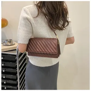 Close-up of brown quilted faux leather shoulder bag with a stylish triple-layered structure