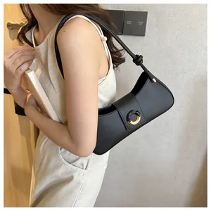 Detail of minimalist black leather half-moon bag featuring a knot-accented shoulder strap