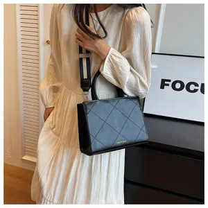 Close-up of black quilted leather crossbody bag with wide strap and gold text logo