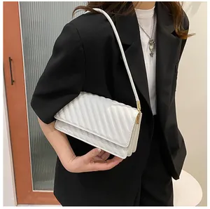 Detail view of a white quilted shoulder bag featuring a sleek flap and gold hardware