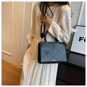 Detail of black quilted crossbody bag featuring a wide striped strap and golden hardware