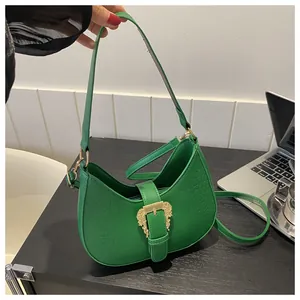 Detail of green crocodile-embossed leather handbag with vintage gold buckle on a desk