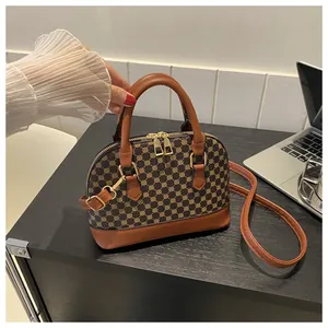 Detail of printed shell crossbody bag with twin zippers and brown leather handles