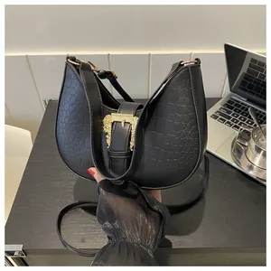 Close-up of black crocodile-embossed hobo bag with vintage gold buckle and metal details