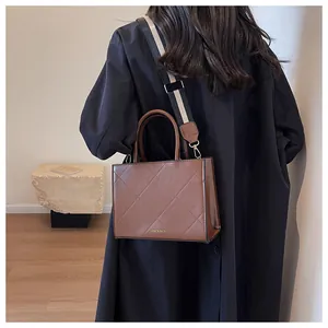 Close-up of brown quilted handbag with broad striped strap and fashion bags lettering
