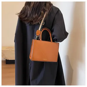 Detail of brown quilted leather bag with stylish striped wide strap on model