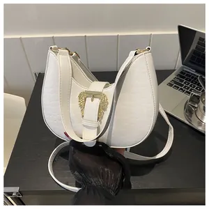 Macro detail of white crocodile-embossed leather and ornate gold baroque buckle on bag