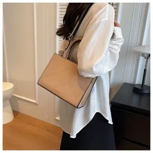 Detail of beige quilted square handbag featuring a top handle and adjustable shoulder strap