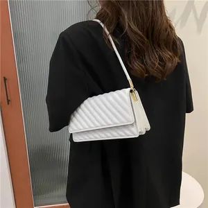 Chic white quilted shoulder bag for women with gold hardware on a black blazer