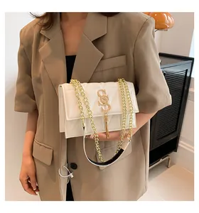 Detail of white quilted crossbody bag with golden S logo and elegant chain strap