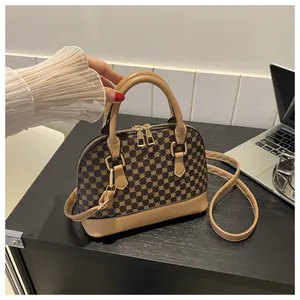 Detailed close-up of shell cross-body bag with brown floral print and gold metal zippers