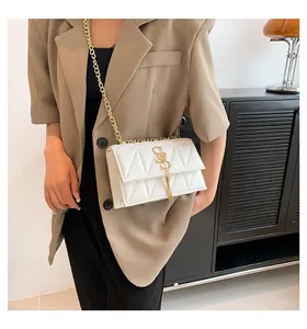 Detail of white quilted handbag featuring gold S-logo and fringe tassel on crossbody strap