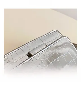 Close-up of shiny silver mirror crossbody bag with realistic crocodile texture