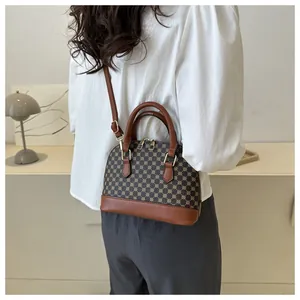 Classic patterned shell handbag worn as a crossbody bag with adjustable strap and top handles