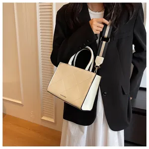 Detail of cream quilted handbag featuring a wide striped shoulder strap and fashion logo