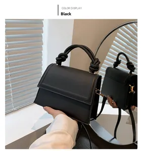 Dettaglio della borsa nera con manico a nodo e texture in pelle liscia opaca di qualità