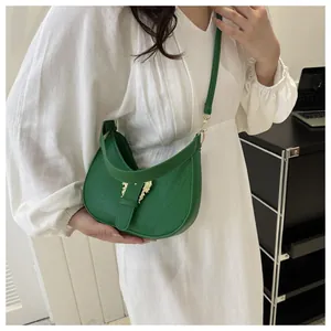 Close-up of green crocodile embossed half-moon bag with gold buckle on a model