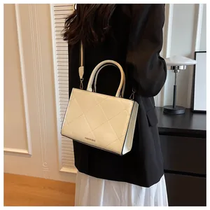 Detail of cream white quilted leather handbag with wide shoulder strap for commuters