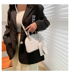 Gros plan d'un sac à main blanc matelassé avec pochette détachable porté à l'épaule