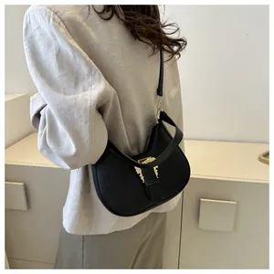Detail of black crocodile texture bag with golden baroque buckle on a gray blazer model