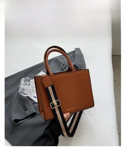 Close-up of brown quilted handbag with wide striped strap on elegant lifestyle background