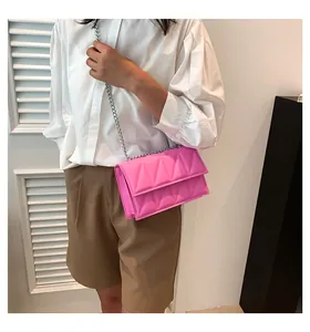 Detailopname van een fuchsia gewatteerde tas met zilveren ketting gedragen door model