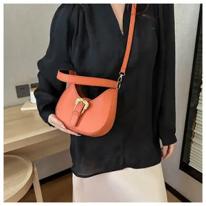 Close-up of orange leather hobo bag with vintage metal buckle and textured finish