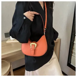 Detail of orange faux leather handbag with baroque gold buckle and lychee texture
