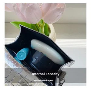 Internal capacity of silver crocodile texture bag showing lipstick and makeup mirror
