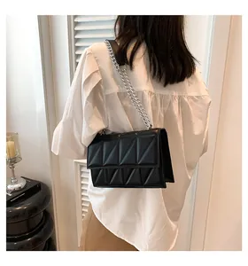 Zwarte gewatteerde crossbodytas met geometrische patronen en zilveren ketting op model