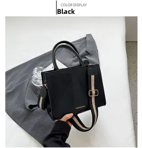 Detail of black quilted PU leather crossbody bag with wide striped strap and top handles