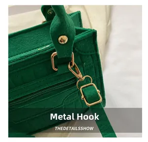 Makrodetail der grünen Handtasche mit Krokoprägung, goldenem Metallhaken und feiner Naht