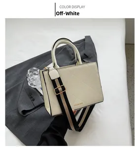 Close-up of creamy white crossbody bag with quilted diamond pattern and wide shoulder strap
