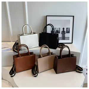 Detail view of stylish square tote bags with quilted texture and wide striped straps