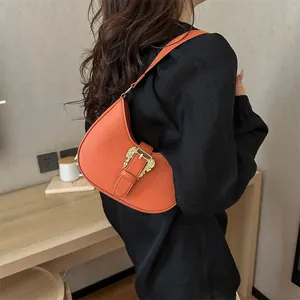 Orange croc-effect crescent bag with vintage gold buckle shown on shoulder model