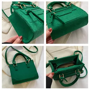 Details einer grünen Handtasche mit Krokodilprägung und Quasten im Motorrad-Stil