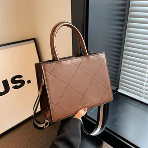 Brown quilted leather handbag with wide striped strap shown in elegant interior setting