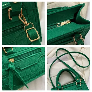 Makroaufnahme einer dunkelgrünen Krokodilmuster-Stofftasche mit goldener Hardware