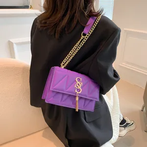 Chic purple crossbody bag with geometric triangle texture and stylish gold S-clasp tassel