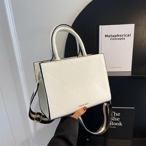 White quilted square tote bag with wide striped shoulder strap and top handles