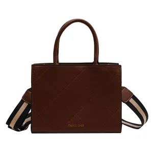 Brown quilted rectangular handbag with wide striped crossbody strap and top handles