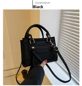Detail einer schwarzen Handtasche mit Krokodilmuster, Goldreißverschluss und Gurt