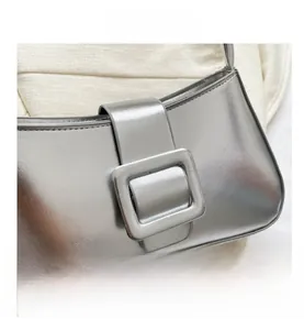 Close-up of a silver metallic mirror handbag with a stylish square buckle on fabric